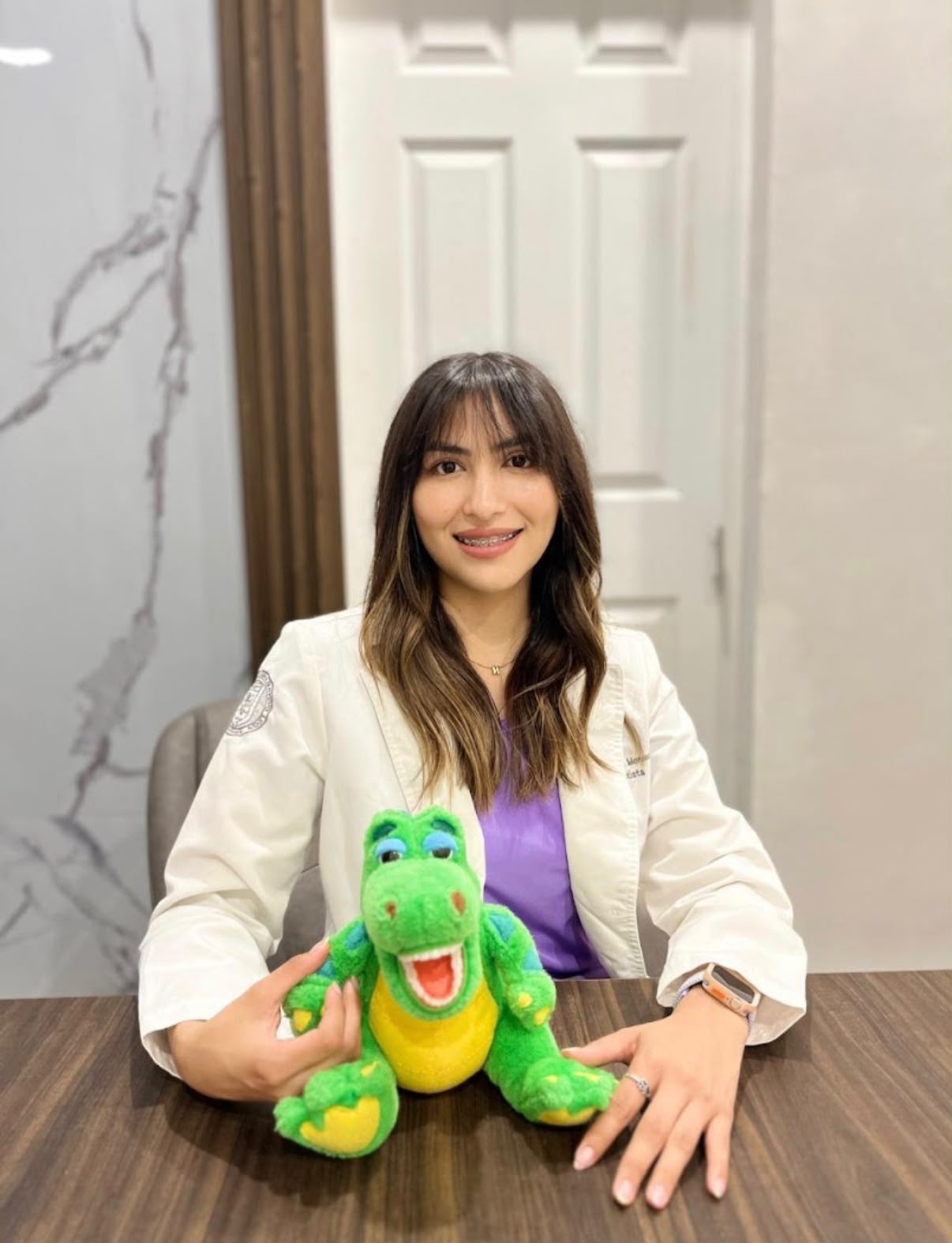 Dra. Nayeli Valadez, odontopediatra, con su mascota dinosaurio en el consultorio